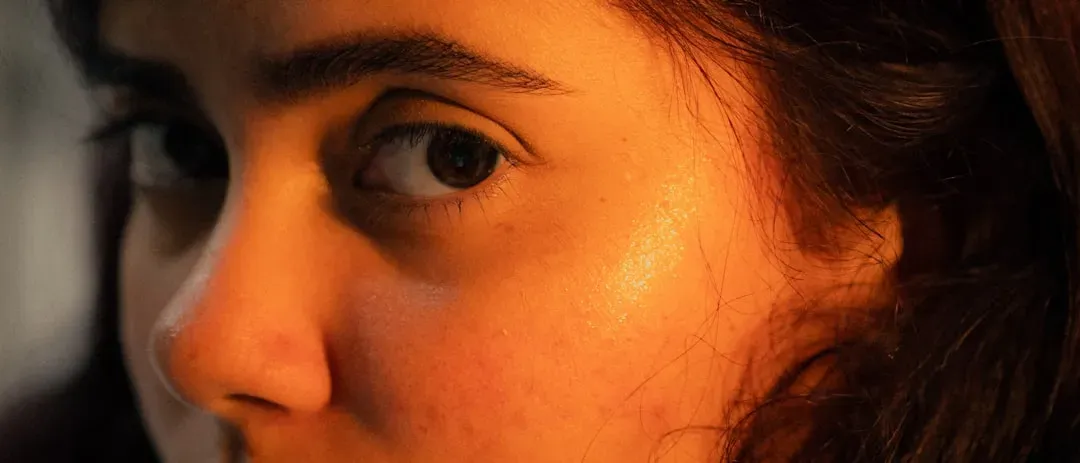 Person with glowing, clear complexion examining radiant skin in natural light, showcasing dry sauna health benefits for skin 