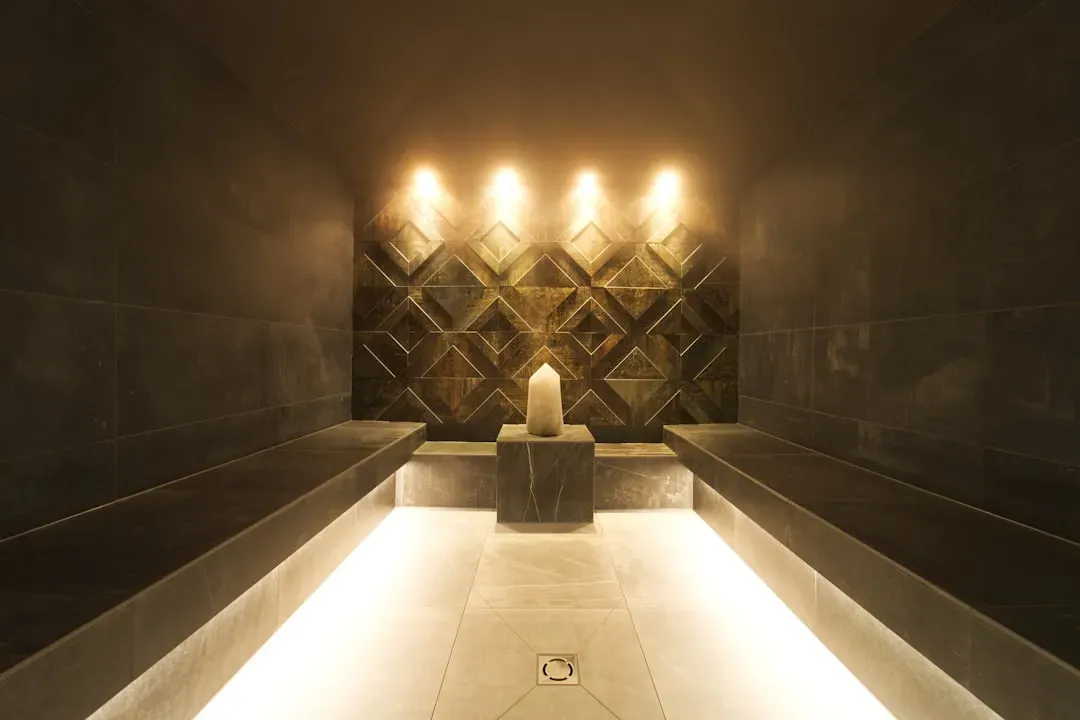 Modern steam room with glass walls, white tiles, and thick steam mist in a contemporary spa setting