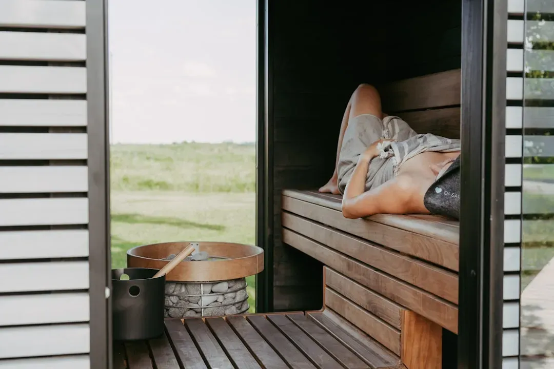 Middle-aged person relaxing peacefully in sauna with glowing skin, demonstrating the calming benefits of sauna use