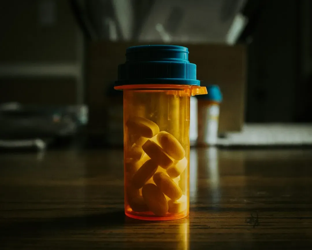 Medication bottles and pills beside water glass, illustrating hydration considerations after sauna use