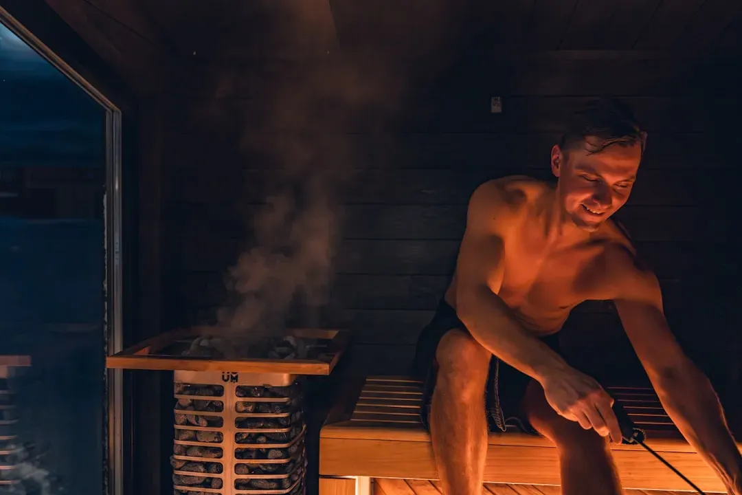 Person relaxing in modern infrared sauna at comfortable lower temperature with visible heating elements for optimal health be