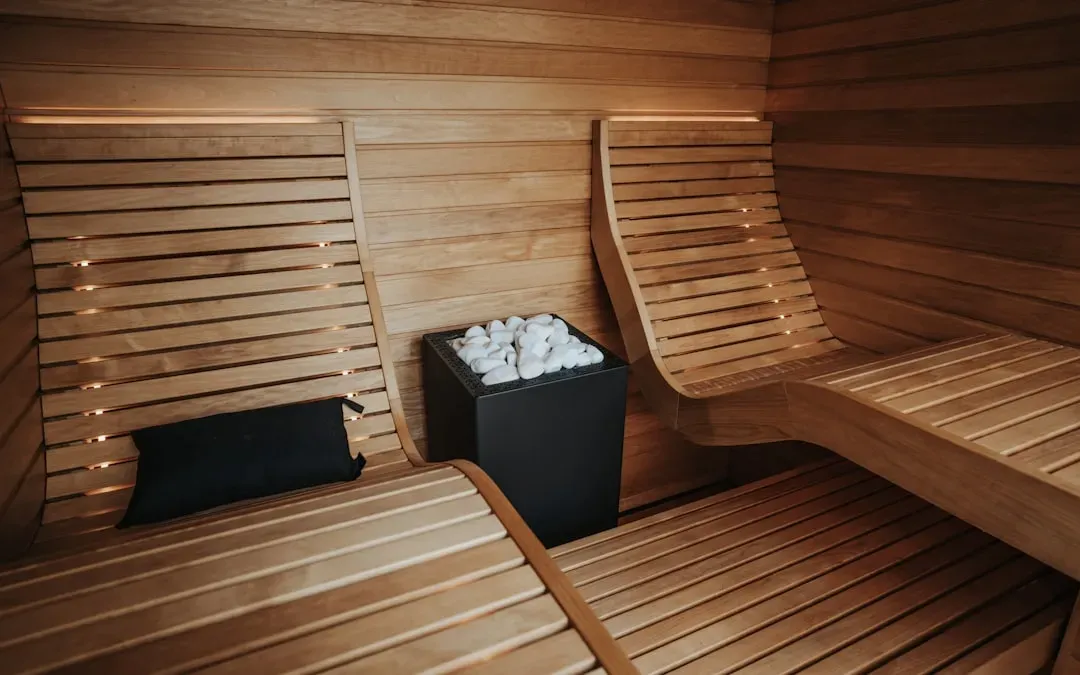 Person relaxing in modern full spectrum infrared sauna cabin with warm wood interior, experiencing therapeutic infrared heat 