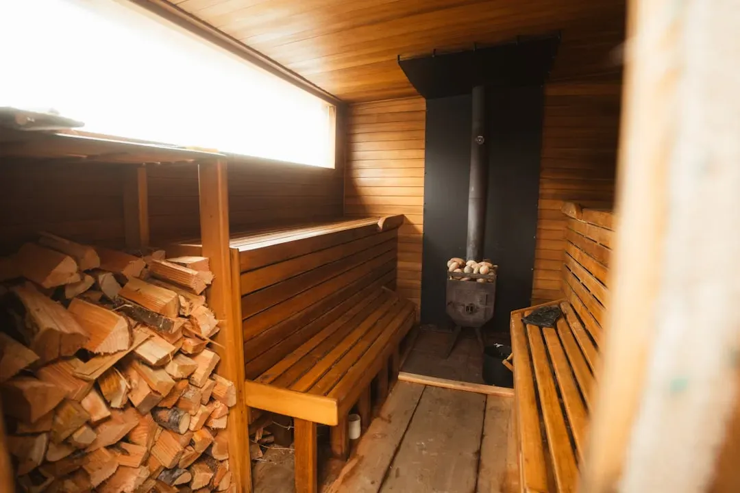 Traditional Finnish sauna interior with wooden benches, steam rising, and person relaxing peacefully on upper bench