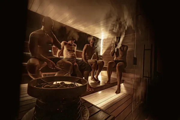 Person relaxing in traditional wooden sauna with steam rising, demonstrating daily sauna benefits for wellness and health res