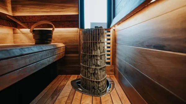 Traditional Finnish sauna interior with wooden benches, golden lighting, and gentle steam rising, demonstrating optimal sauna