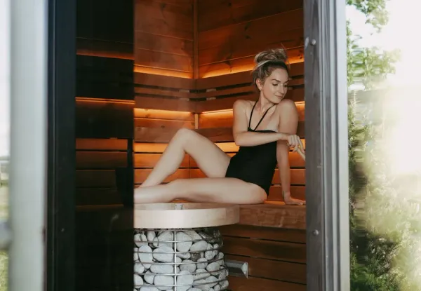 Woman in her 50s relaxing peacefully in a traditional wooden sauna with steam rising, experiencing sauna benefits for women's