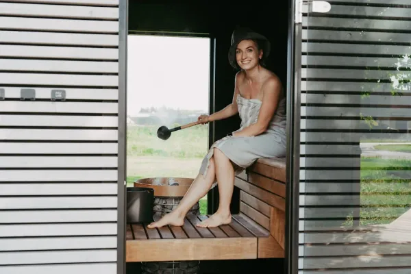 Peaceful person relaxing in traditional wooden sauna with steam, demonstrating sauna benefits for improved sleep quality and 