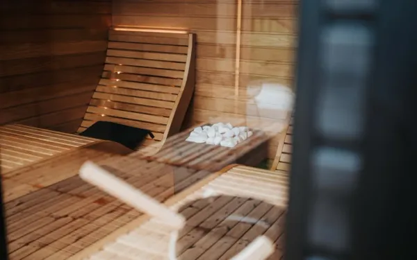 Traditional Finnish sauna interior with wooden benches, glowing heated stones, and gentle steam demonstrating safe beginner s